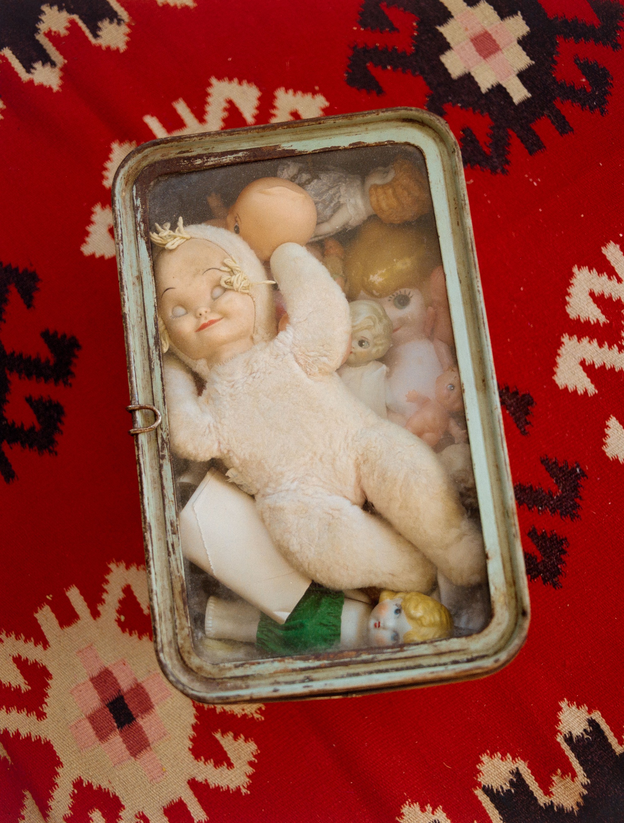 Vintage doll collection in a glass shadow box on a kilim rug in Addeline Griswold's Los Angeles studio, medium format film photograph by Nathaniel Perales