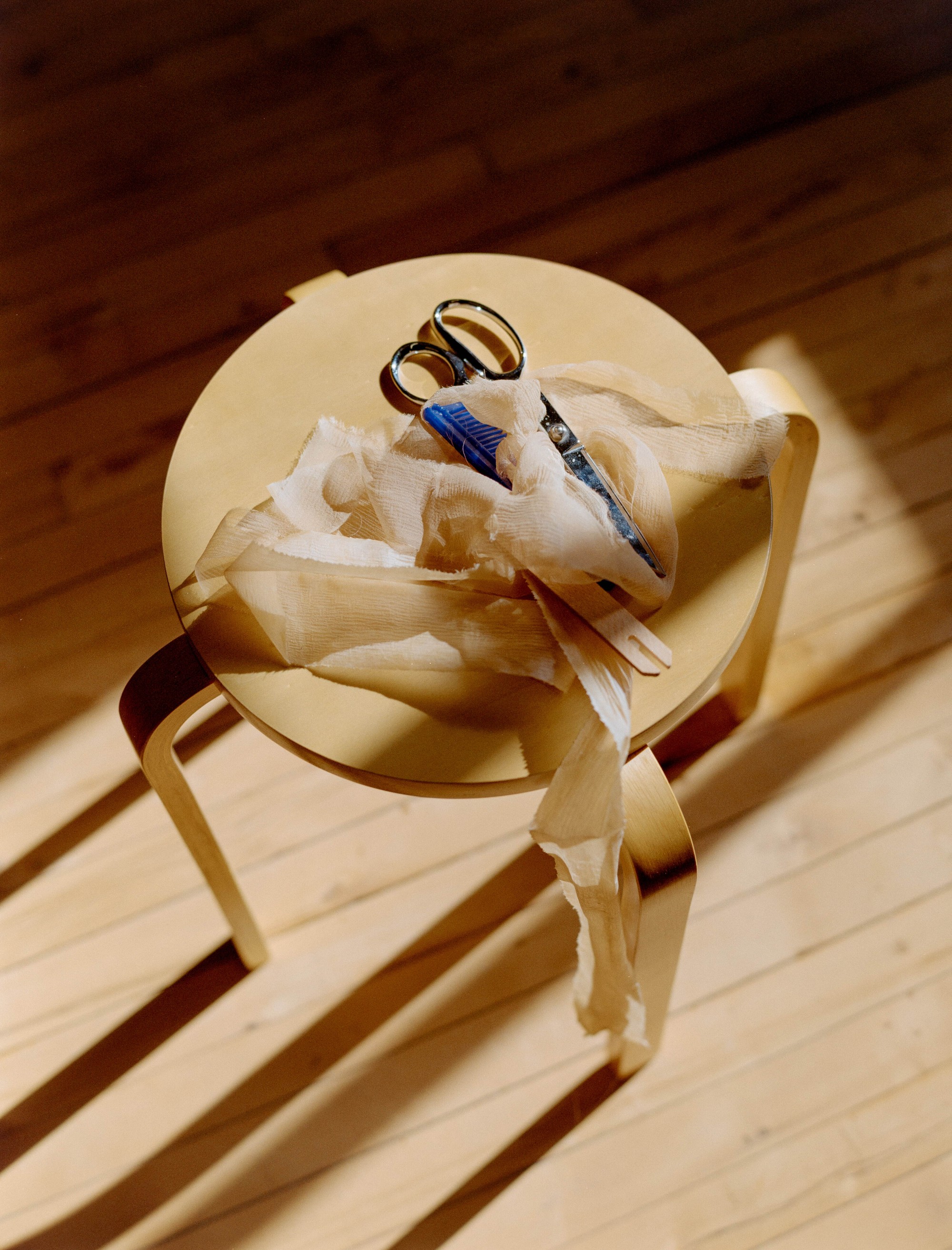 Naturally dyed silk and scissors on a wooden stool in Laura Kung's Portland studio, shot on medium format film