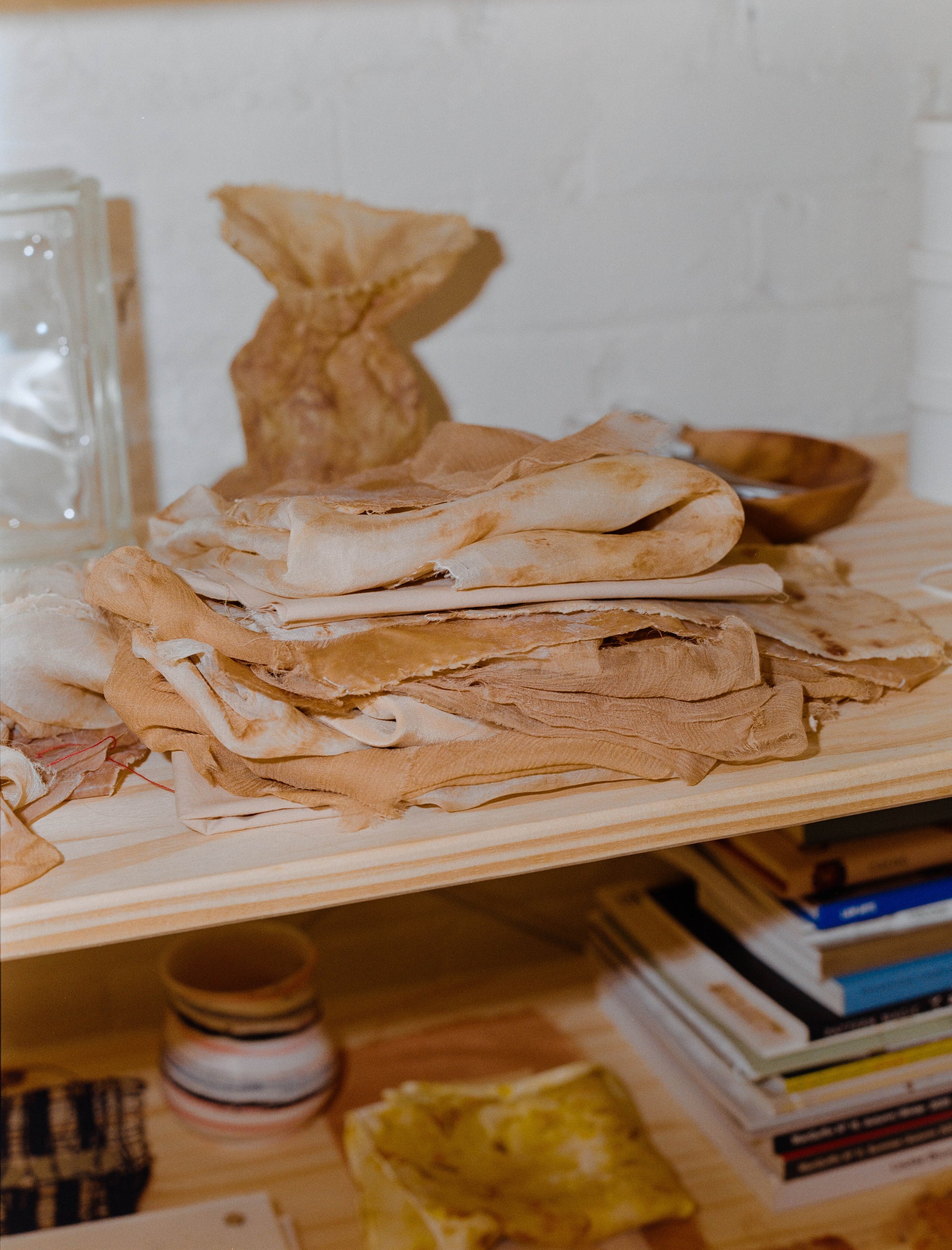 Stack of naturally dyed silk fabric on a studio shelf, Portland textile artist Laura Kung, shot on medium format film