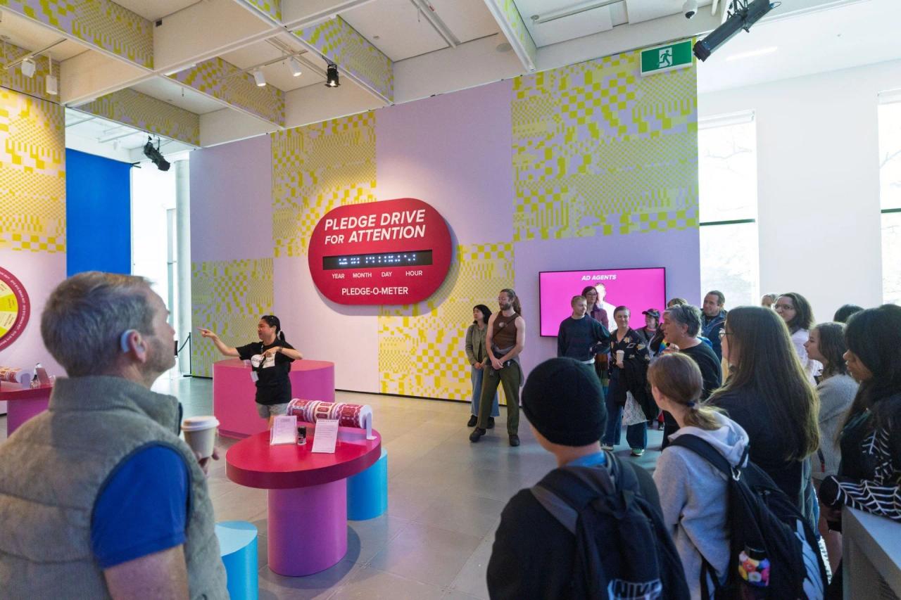 A facilitator signs to a group of visitors during a tour of a colourful Science Gallery Melbourne exhibition.