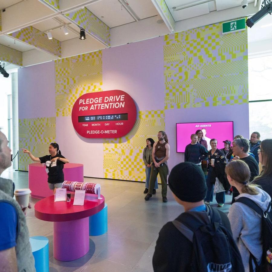 A facilitator signs to a group of visitors during a tour of a colourful Science Gallery Melbourne exhibition.