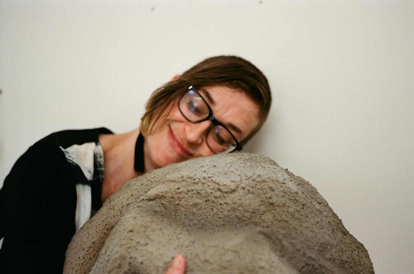 Elizabeth Reed resting her head on a sculpted boulder
