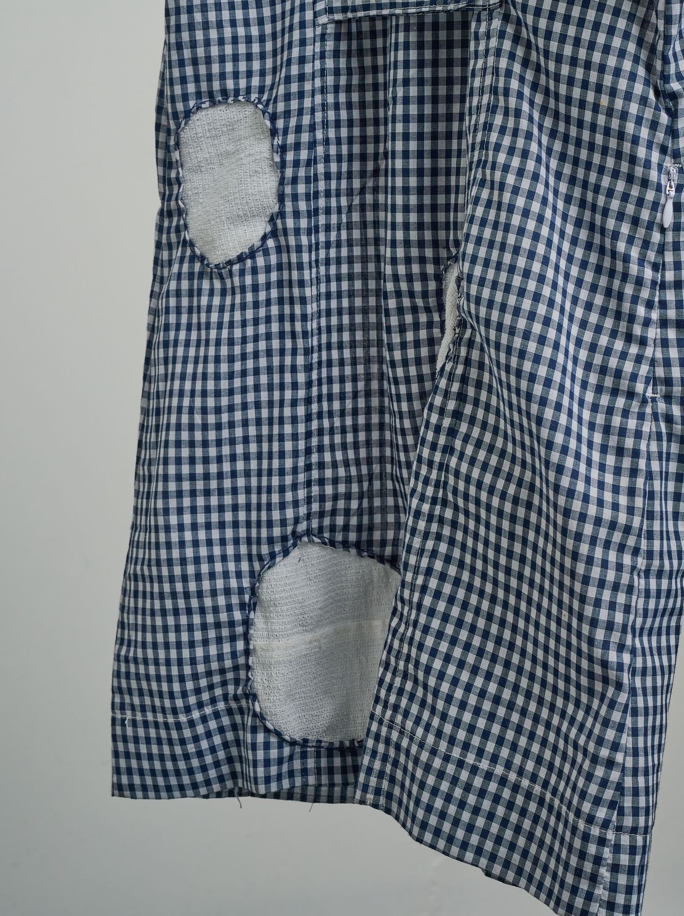 Detail — patched holes along the hem of the dress