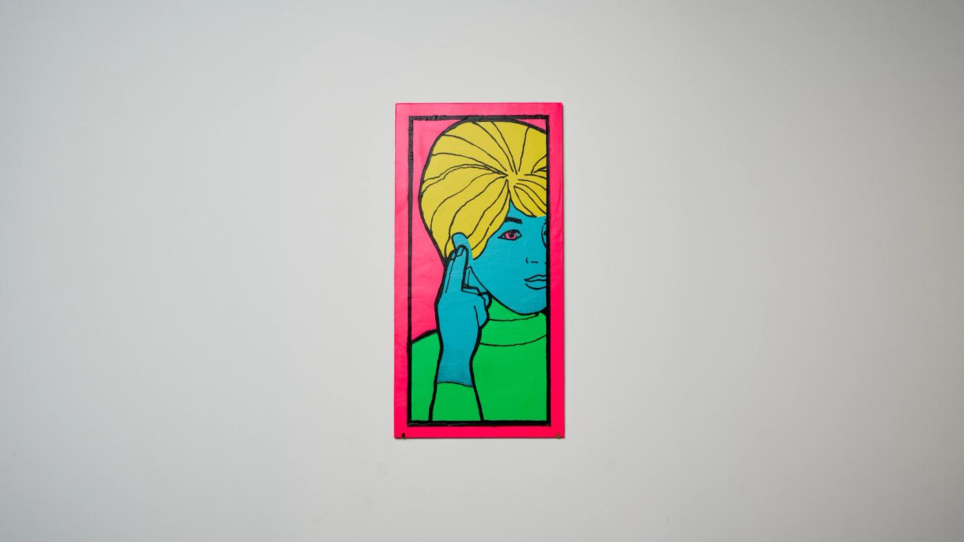 [DEAF] — enamel plate in fluoro pink and green showing the Auslan sign for deaf, hung on a white wall