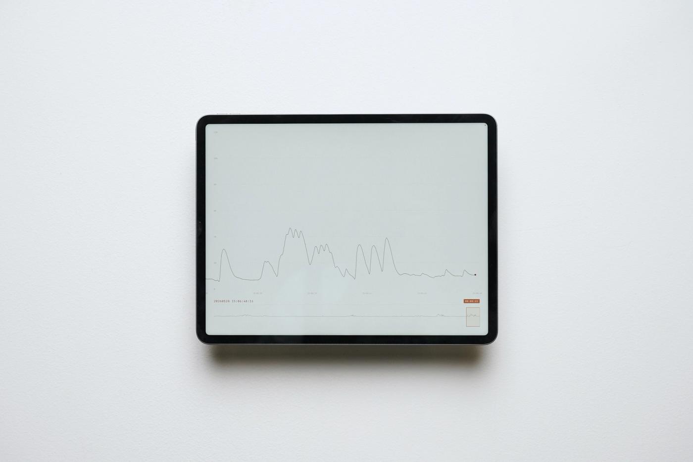 Seismic Shifts — screen mounted on a white wall drawing the room’s acoustic energy as a scrolling line