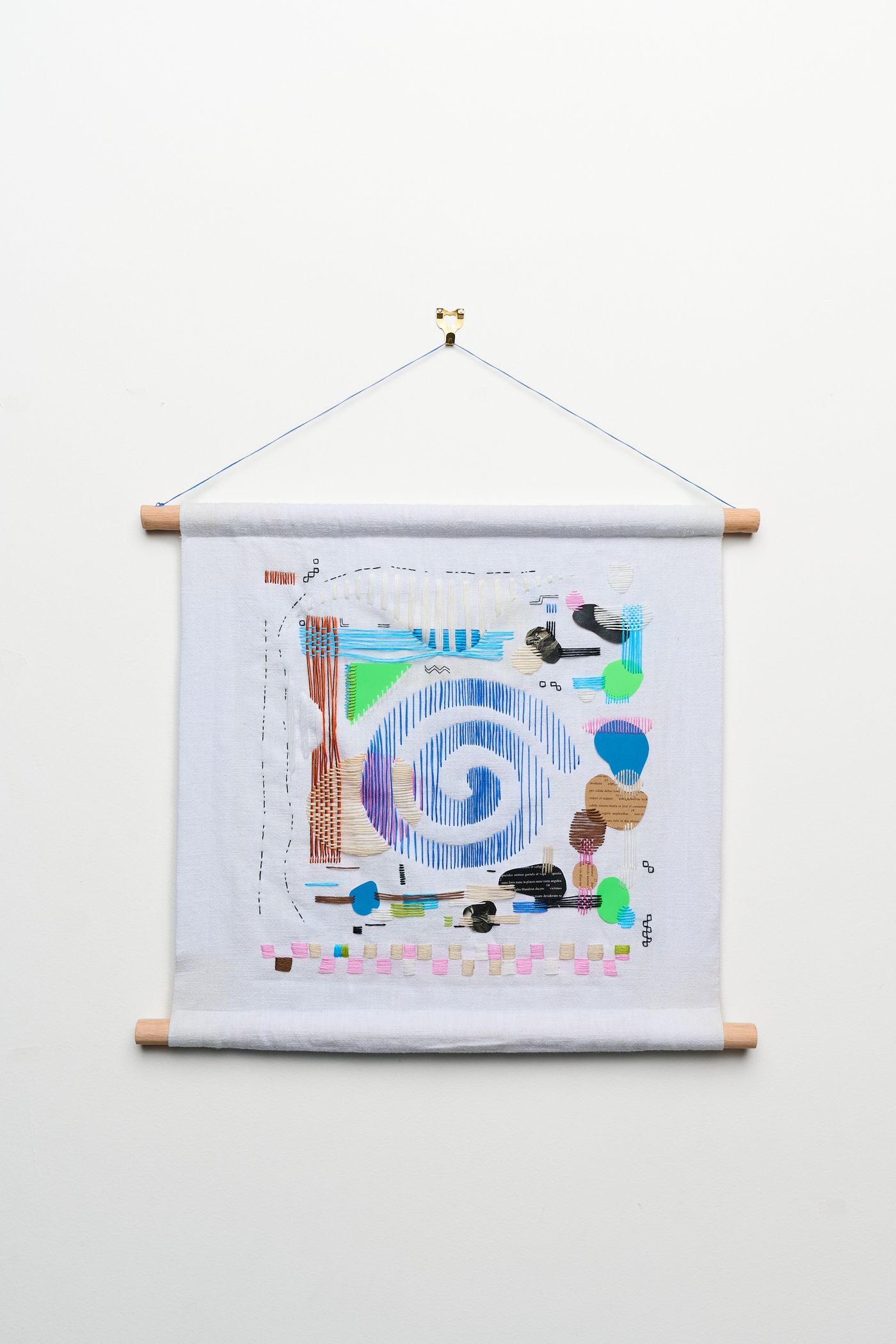 Tabula Rasa Pt 1 — white textile hanging with a blue embroidered spiral surrounded by stitched fragments