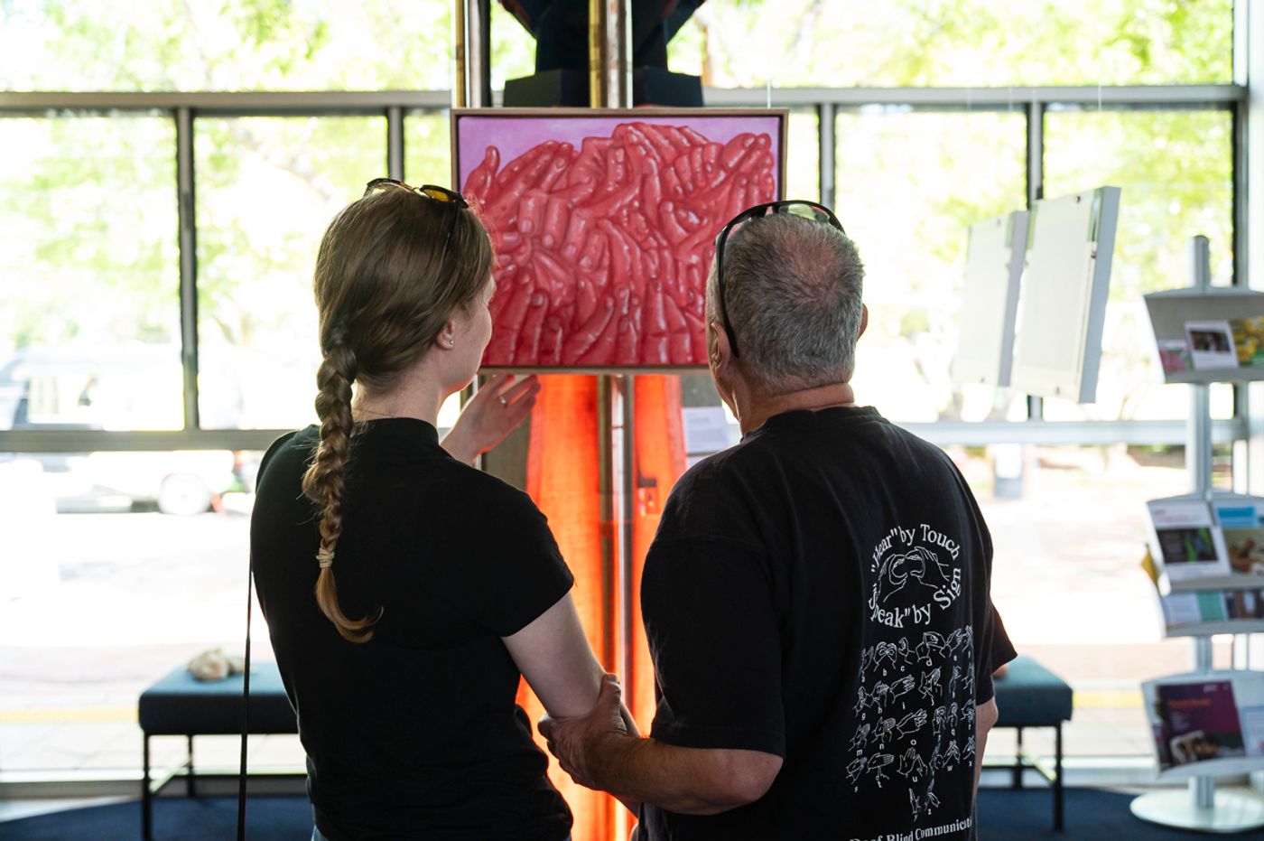 Visitors viewing Spicy — a red painting of clustered signing hands — at Flow Festival