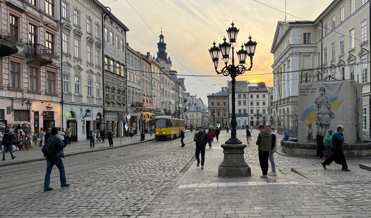 People walking around Rynok Square in Lviv at sunset