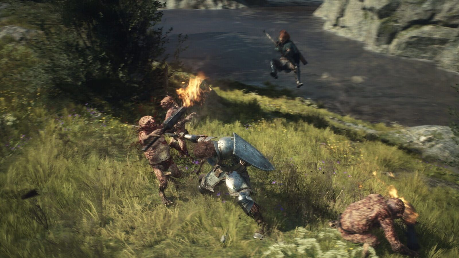 An armoured fighter with a round shield battles goblins on a grassy riverbank while an ally leaps overhead