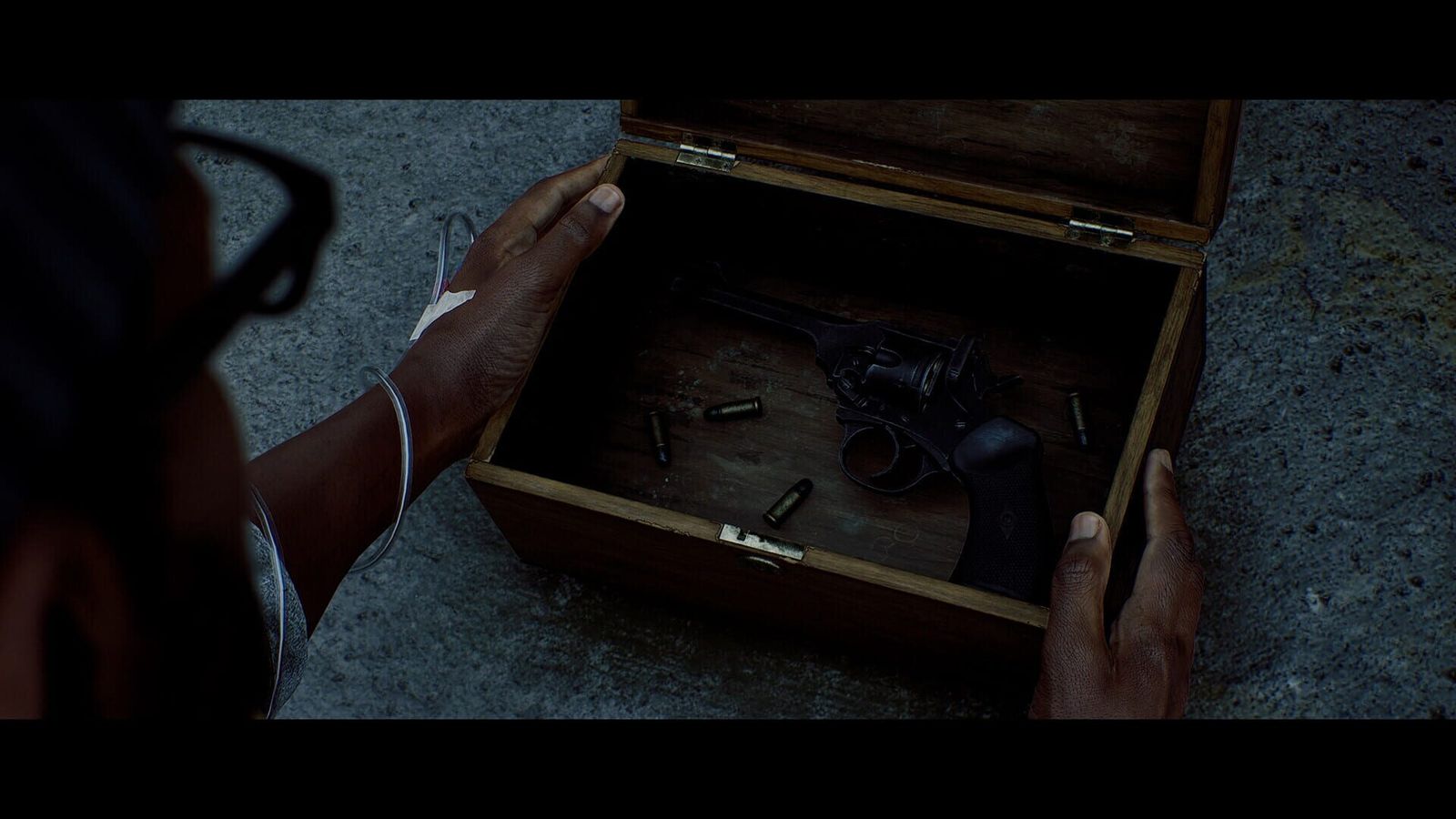 Hands opening a wooden case containing a revolver and loose bullets