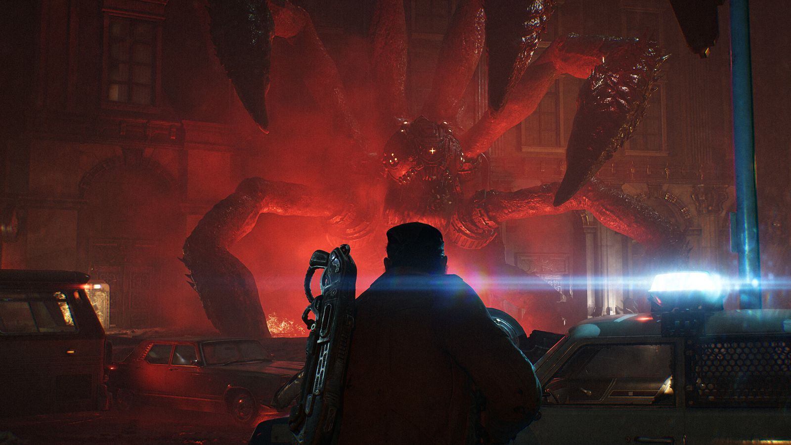 A soldier seen from behind faces a huge tentacled creature glowing red above wrecked cars
