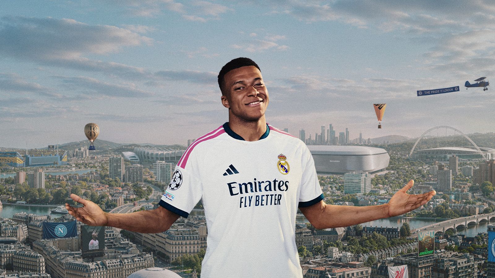 A footballer in a white kit spreads his arms in front of a wide city skyline with stadiums and a river
