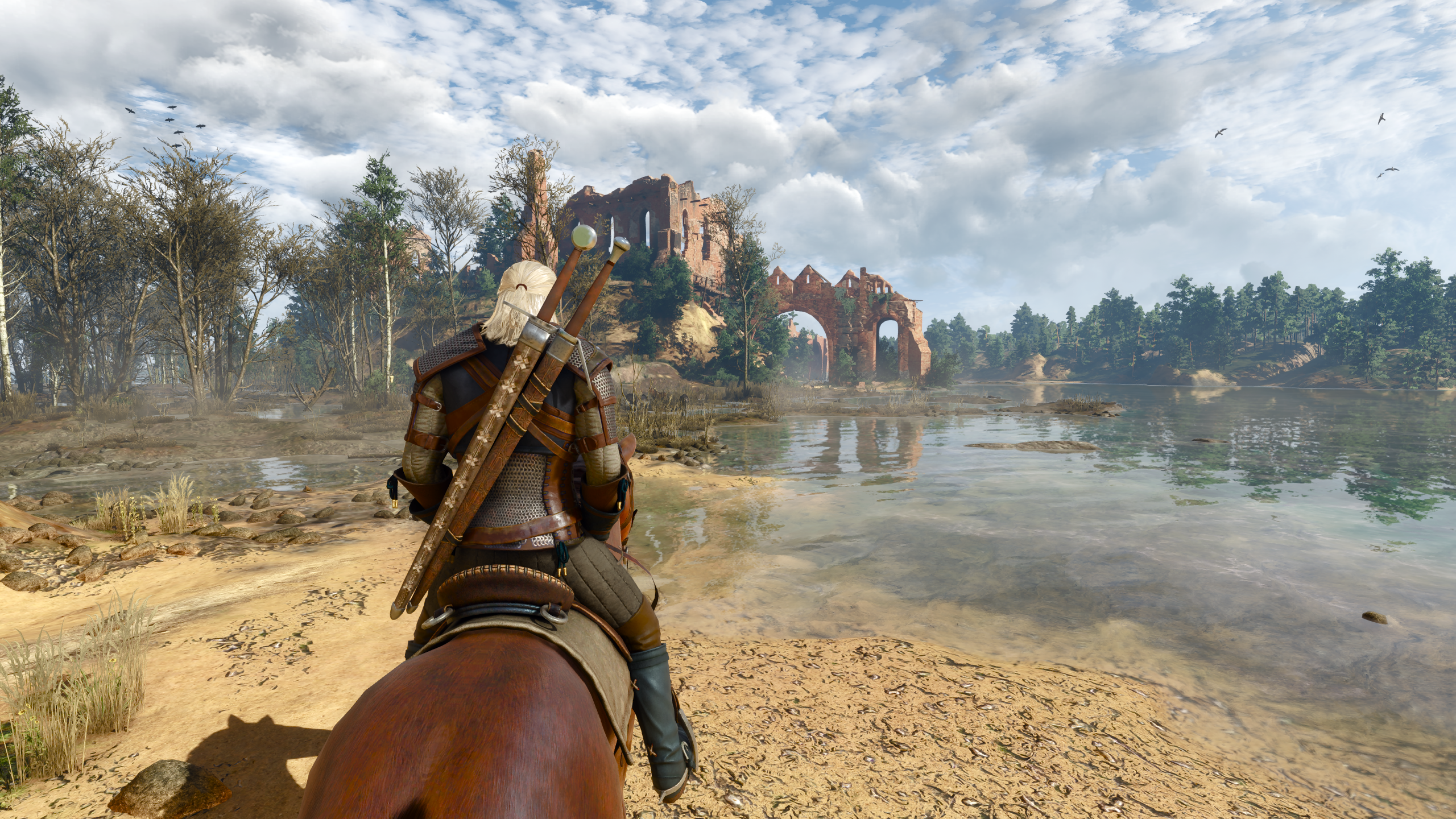 Geralt riding his horse Roach along a sandy lake shore towards stone ruins