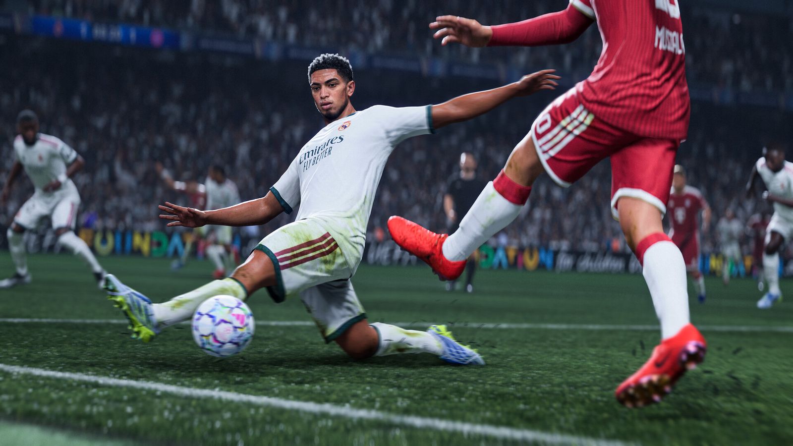 A player in a white kit slides to reach the ball as a defender in red lunges in, in a floodlit stadium