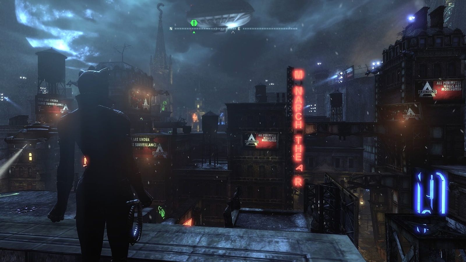 Catwoman standing on a rooftop above Arkham City at night, with neon signs and searchlights below
