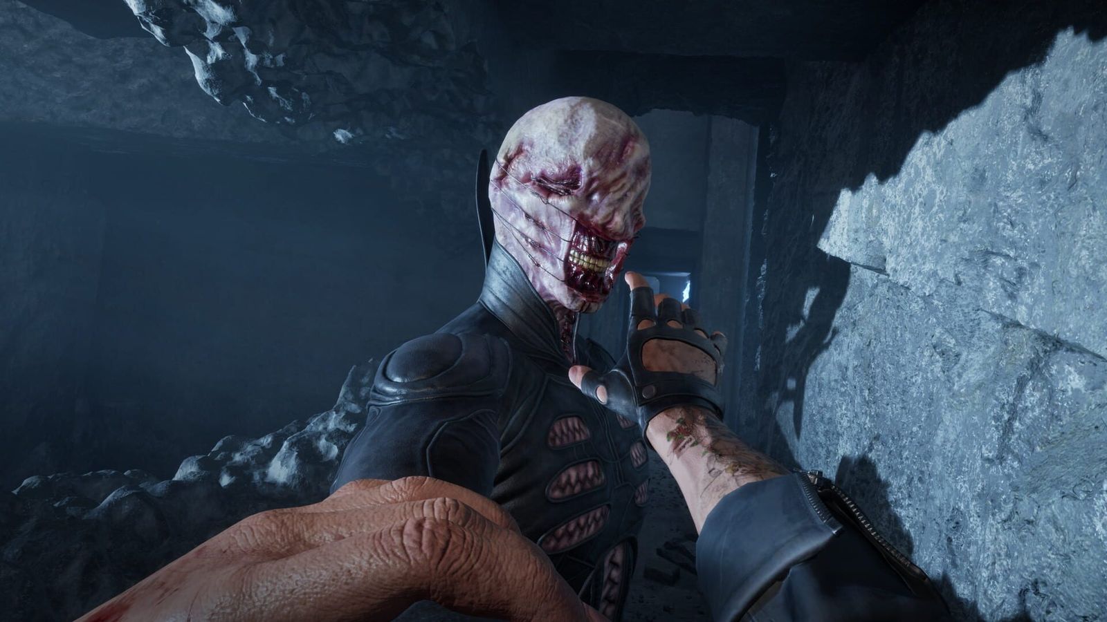 A Cenobite with exposed teeth and a flayed face lunges at the player in a dark stone corridor