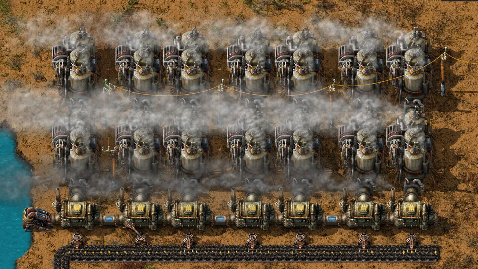Factorio screenshot of two long rows of steam engines and boilers venting white smoke next to a coastline and a conveyor belt