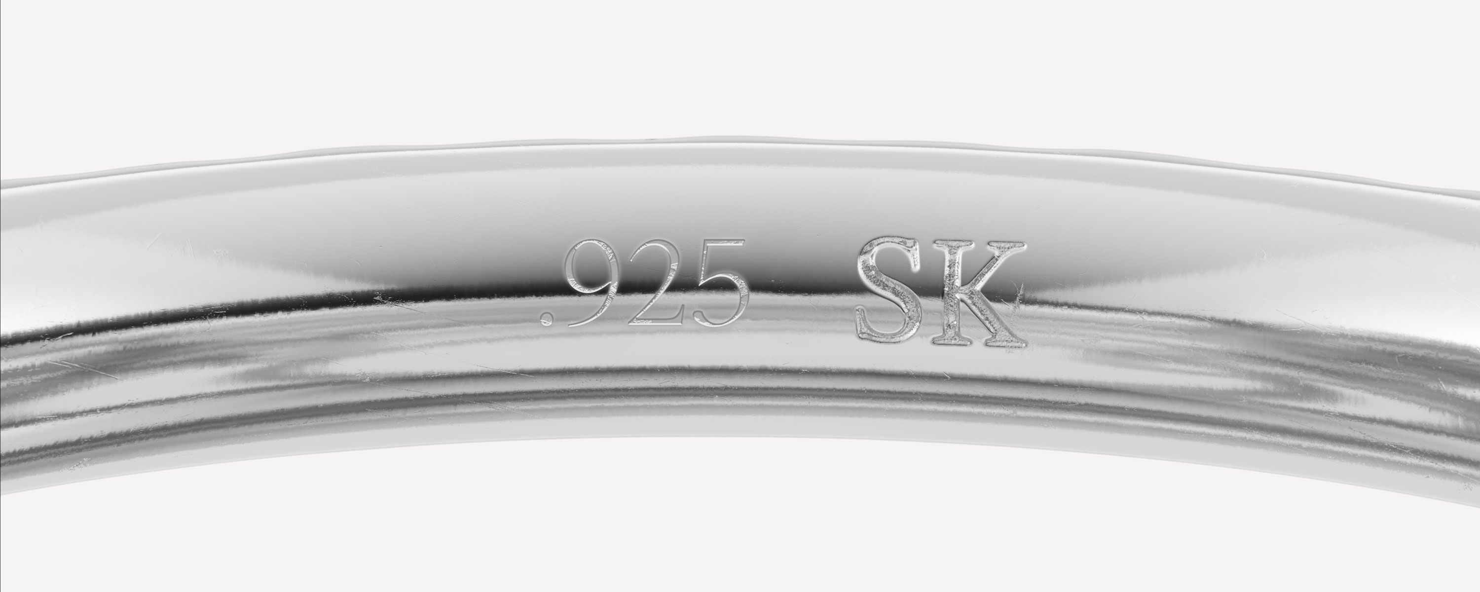Close-up image of the interior of a Spinelli Kilcollin silver ring with ".925" and "SK" hallmark stamps featured on white background