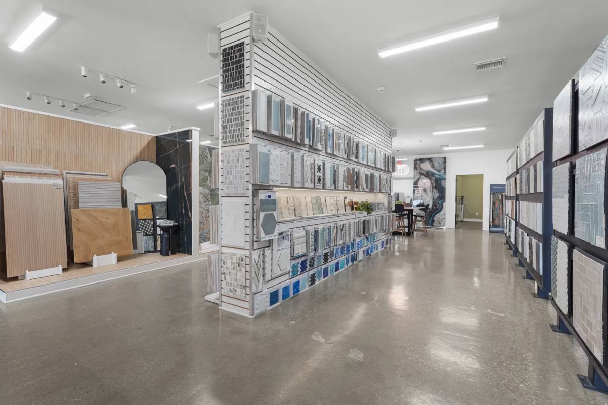 An aisle of upright porcelain tile sample racks running the length of the SRQ Modern showroom