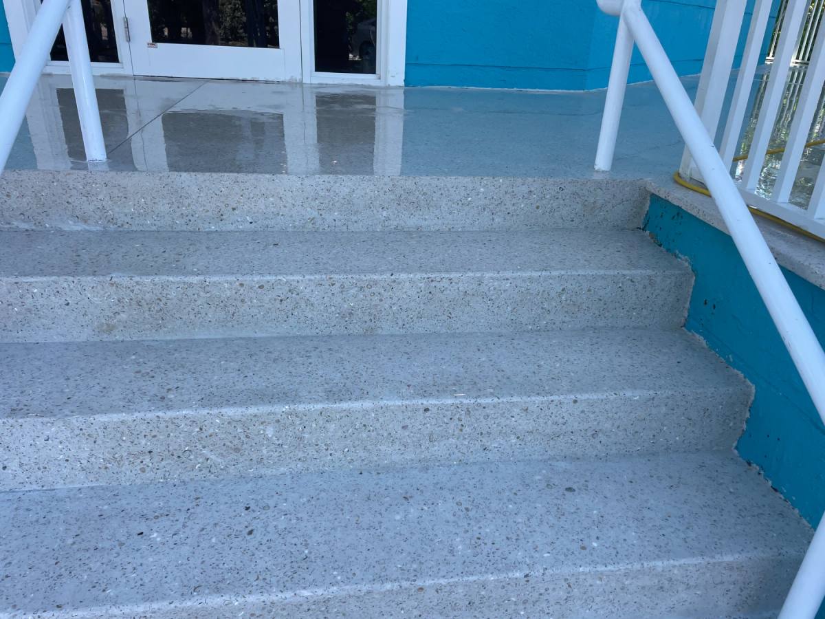 Shellcrete steps down to a pool, the shell aggregate visible in the tread, a white rail alongside