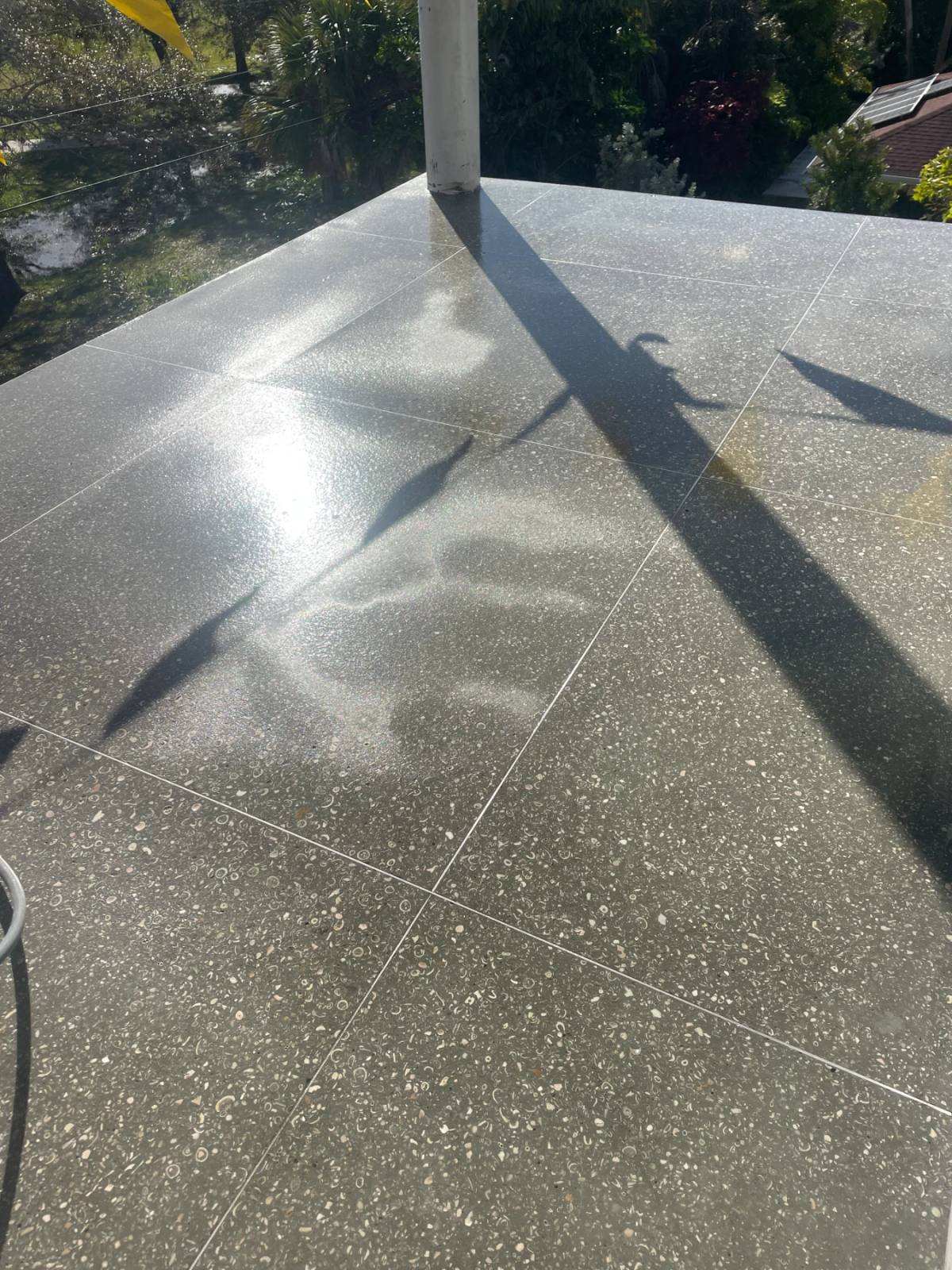 Grey Shellcrete deck in large squares running out to a white column, wet and reflective in low sun
