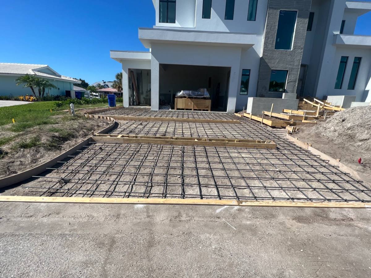 A large formed slab with the reinforcing mat laid out, ready for a pour, a modern building behind it