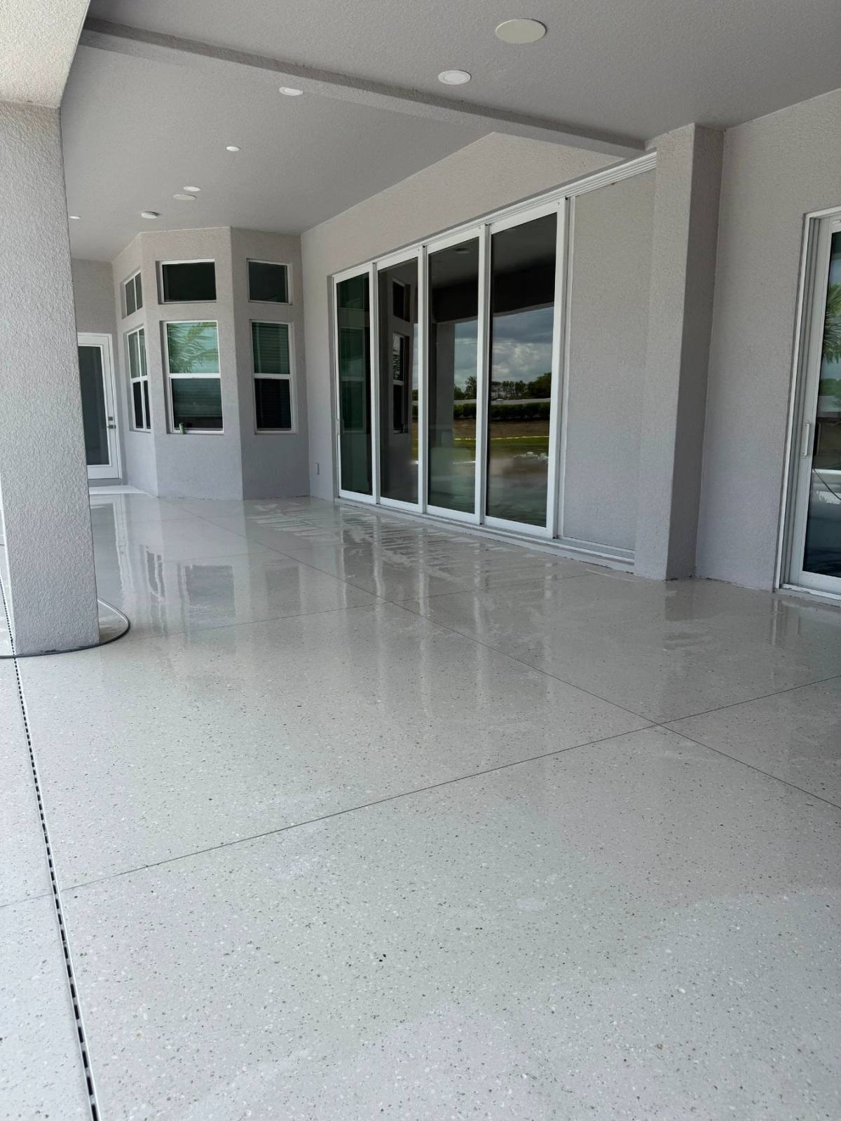 Covered lanai with a high-gloss polished Shellcrete floor in large panels reflecting the sliding glass doors