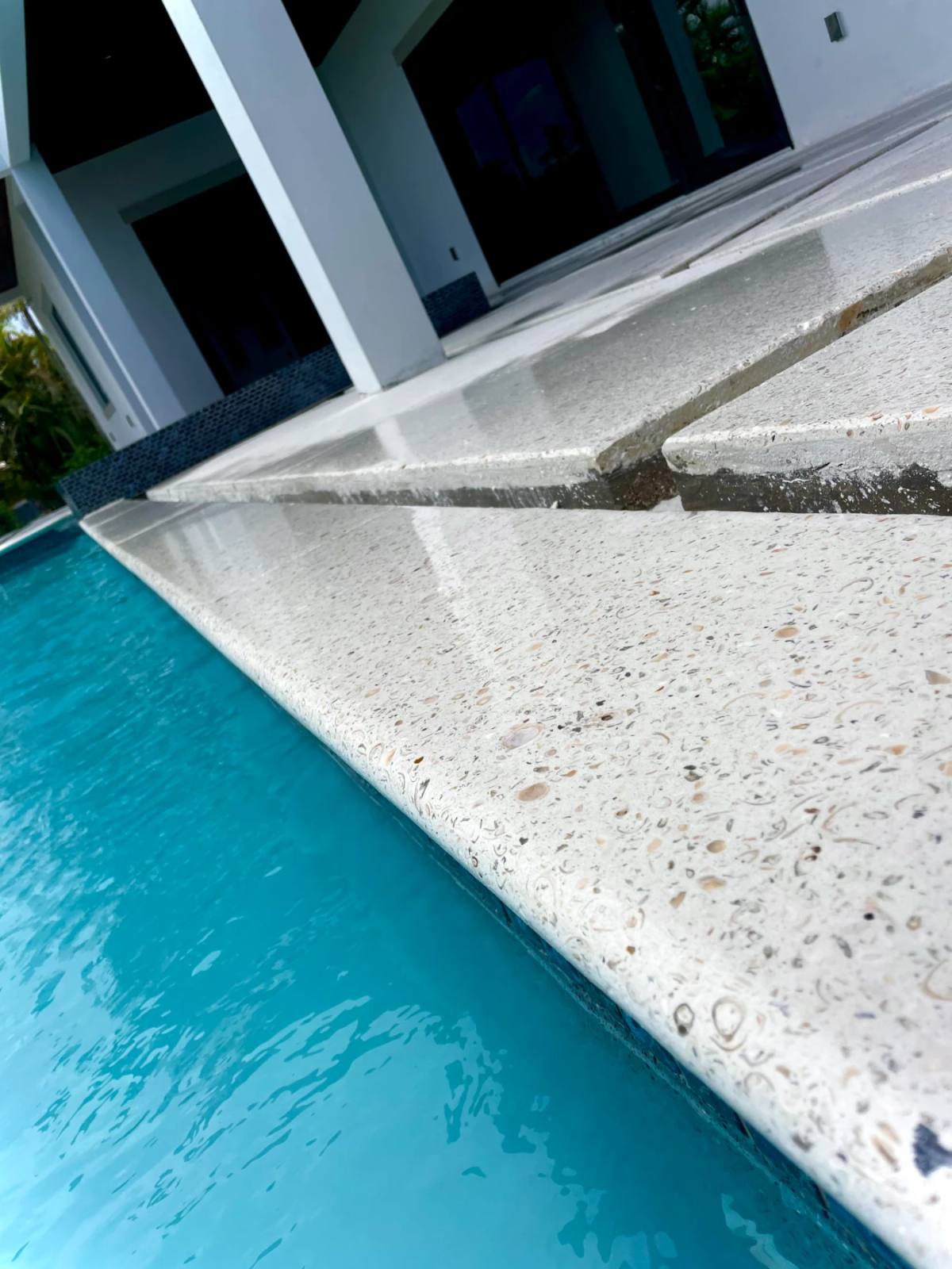 Shellcrete pool coping meeting bright turquoise water, the mitred edge and top face dense with whole shells