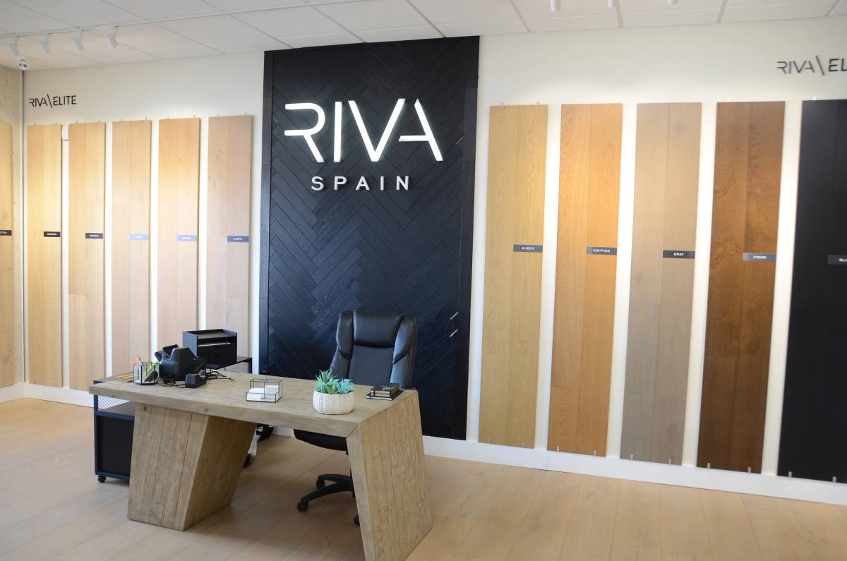 The Riva Spain gallery at SRQ Modern — a desk in front of a wall of wide-plank wood samples