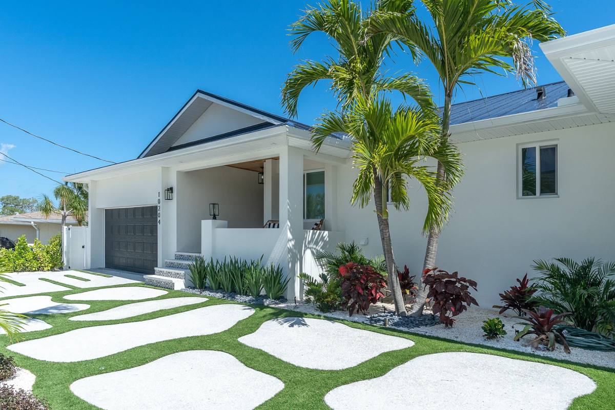 Freeform islands of pale Shellcrete set into artificial turf, running to a white modern house