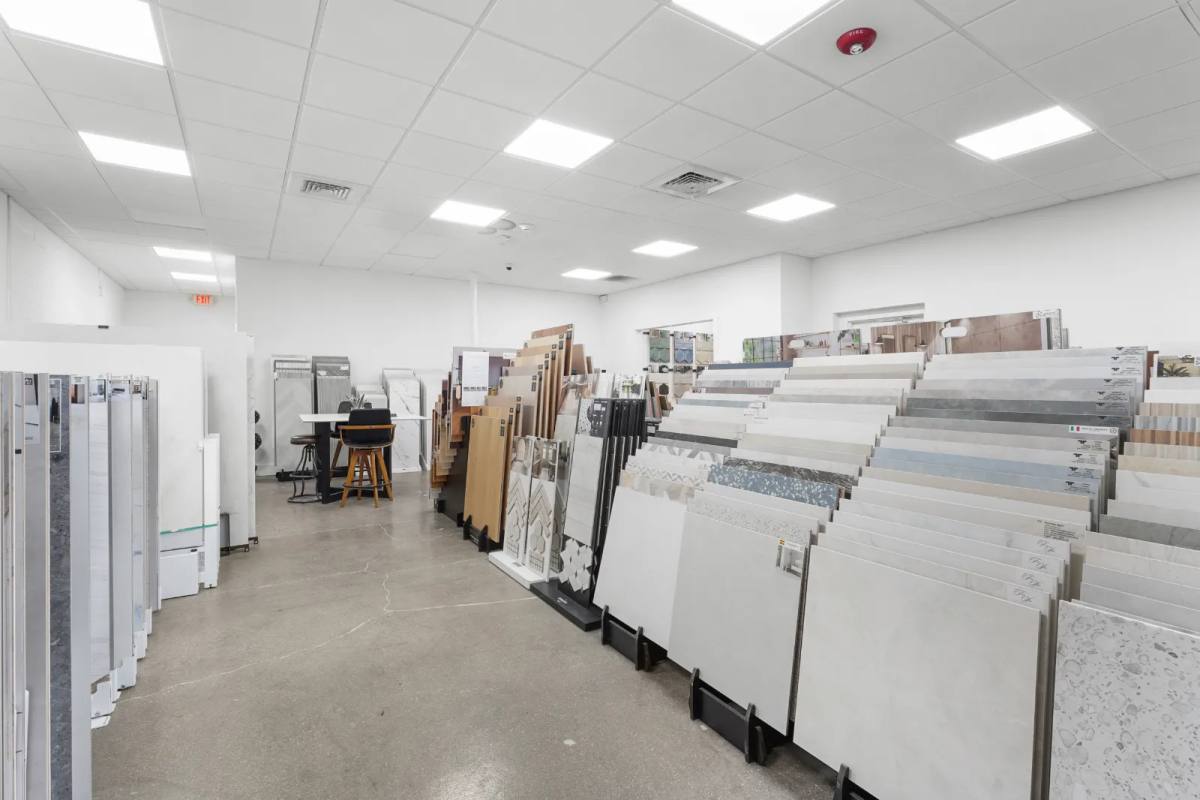 Rows of large porcelain sample boards standing on floor racks down a bright tile showroom aisle