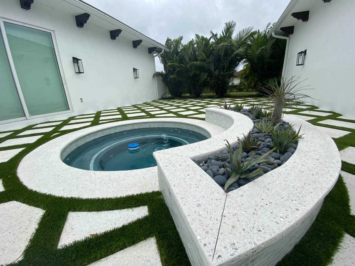 A curved shellcrete spa surround and planter, poured in place, with turf set into the deck around it