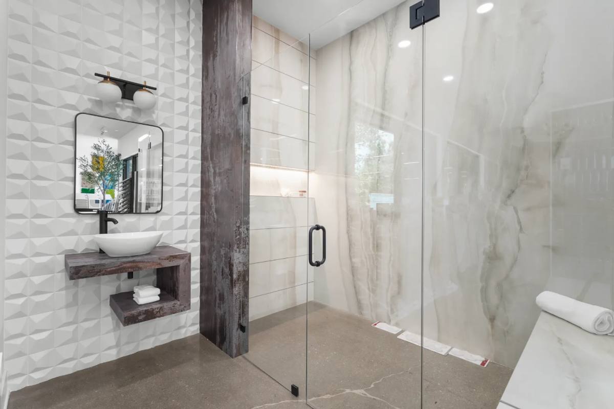 A shower in marble-look porcelain with a glass door and a wood vanity