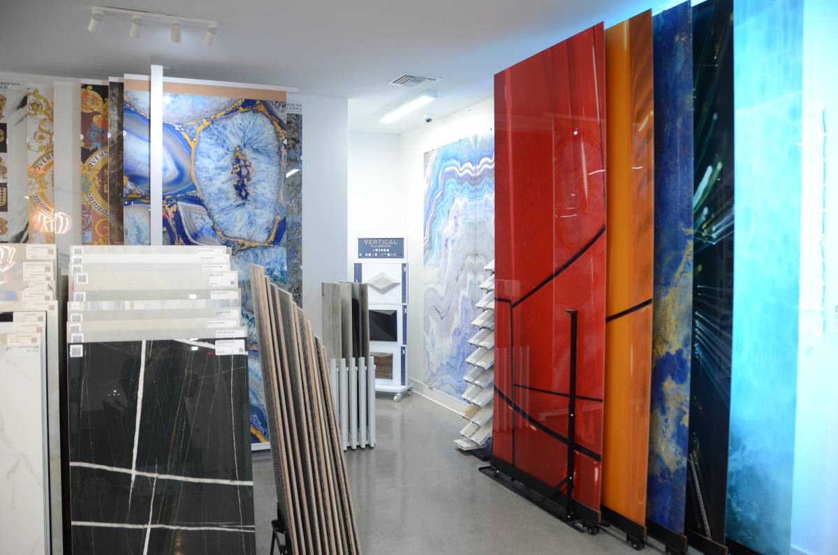 Full-height decorative slabs in the showroom — blue agate, red and teal panels beside black marble