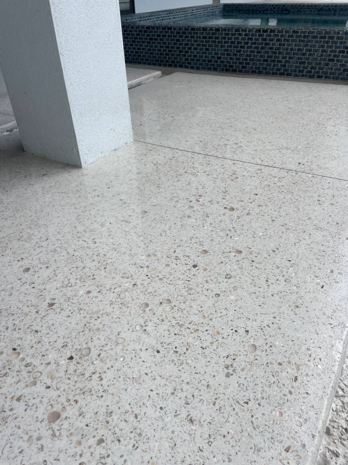 Polished Shellcrete deck crowded with whole clam shells and spiral fragments beside a dark blue mosaic spa wall