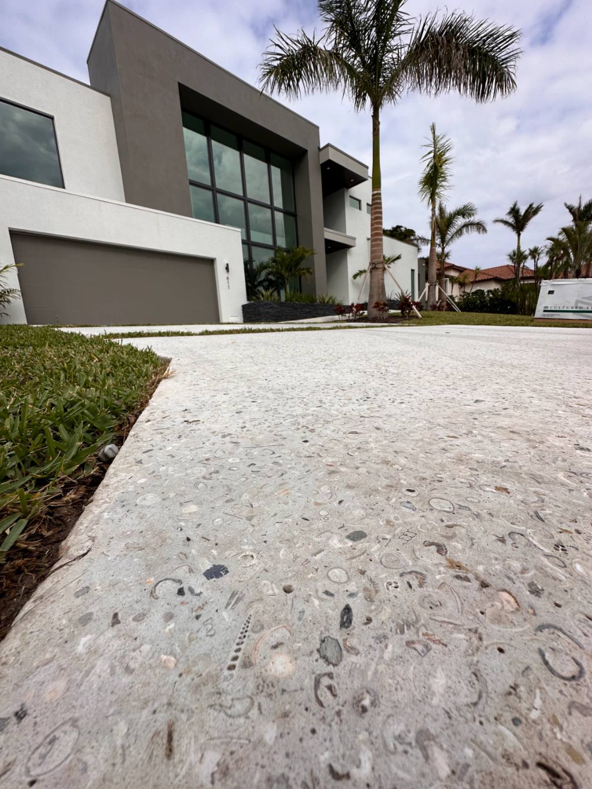 A ground-level view across a Shellcrete driveway, the surface dense with shell rings