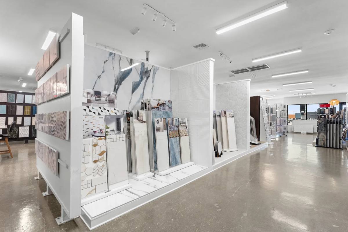 Tile showroom display walls of marble-look porcelain, textured white tile and sample panels on a polished concrete floor