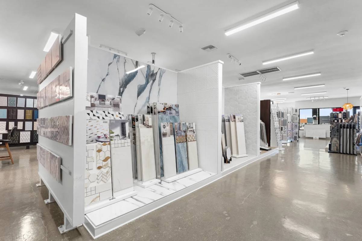 Tile showroom display walls of marble-look porcelain, textured white tile and sample panels on a polished concrete floor