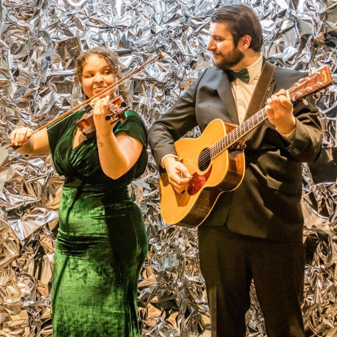 Man and woman pose with instruments, man smiles while woman give him a sassy look.