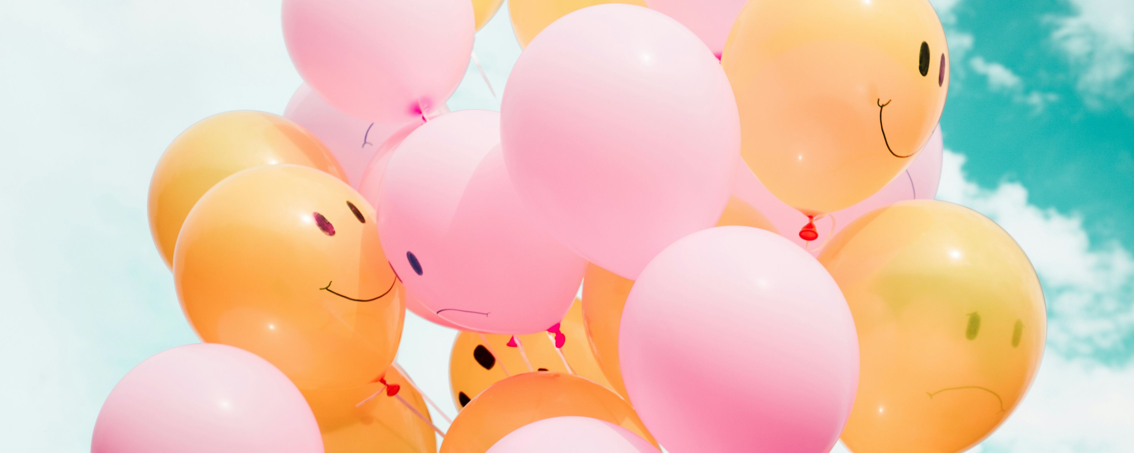 a bunch of balloons with smiley faces on them are flying in the sky .