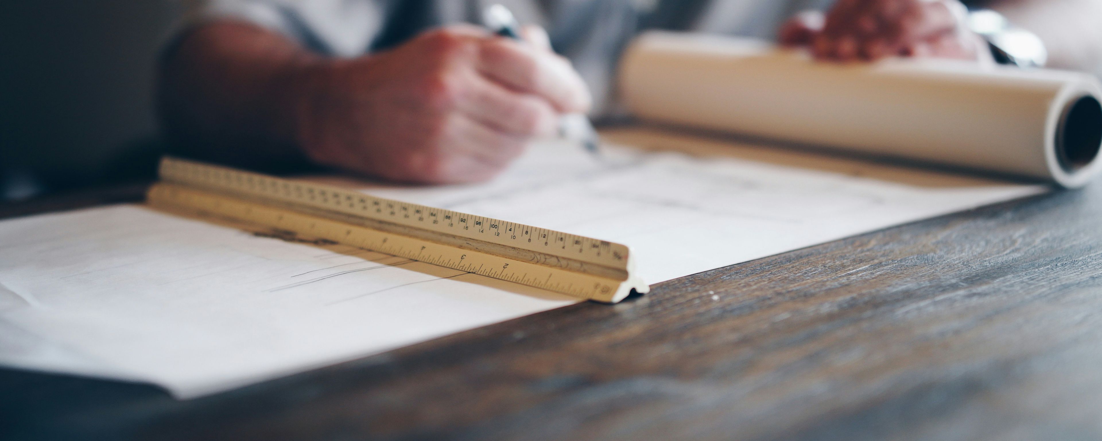 a man is sitting at a table with a ruler and a pen .