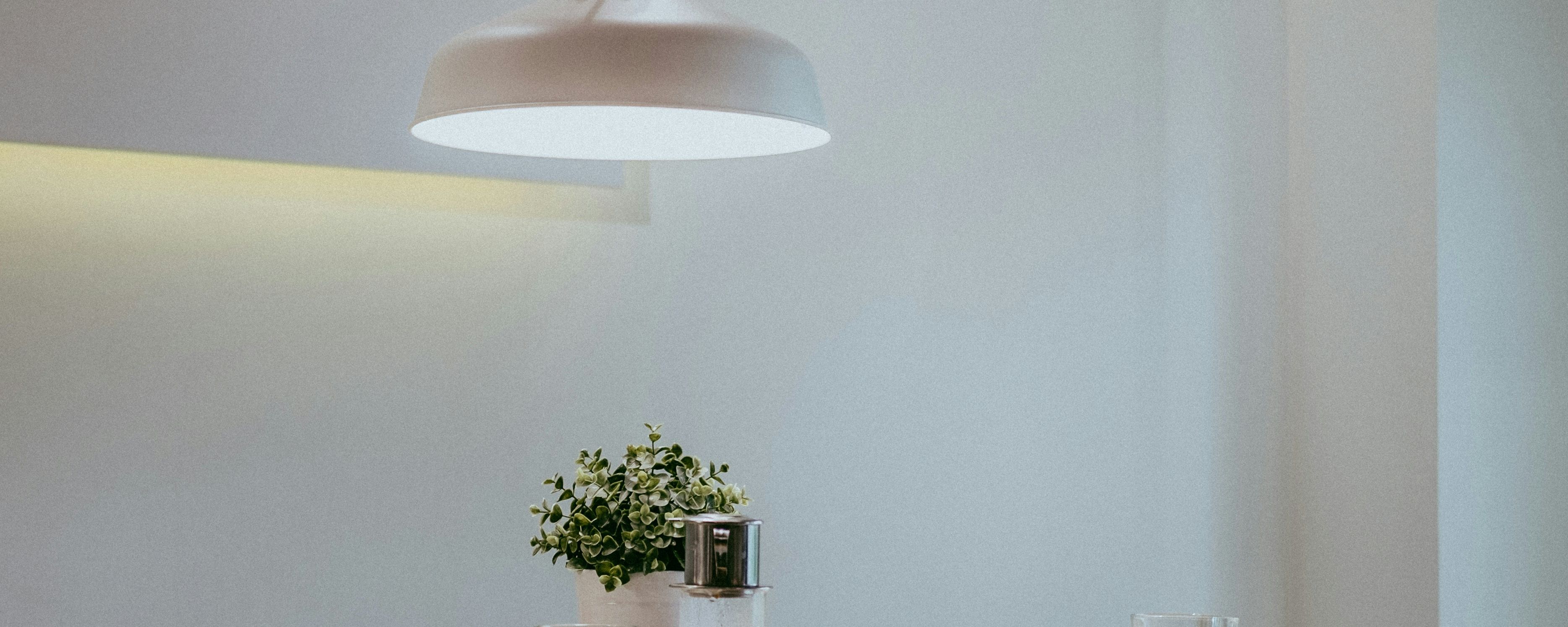 a dining room table with a white pendant light hanging from the ceiling .