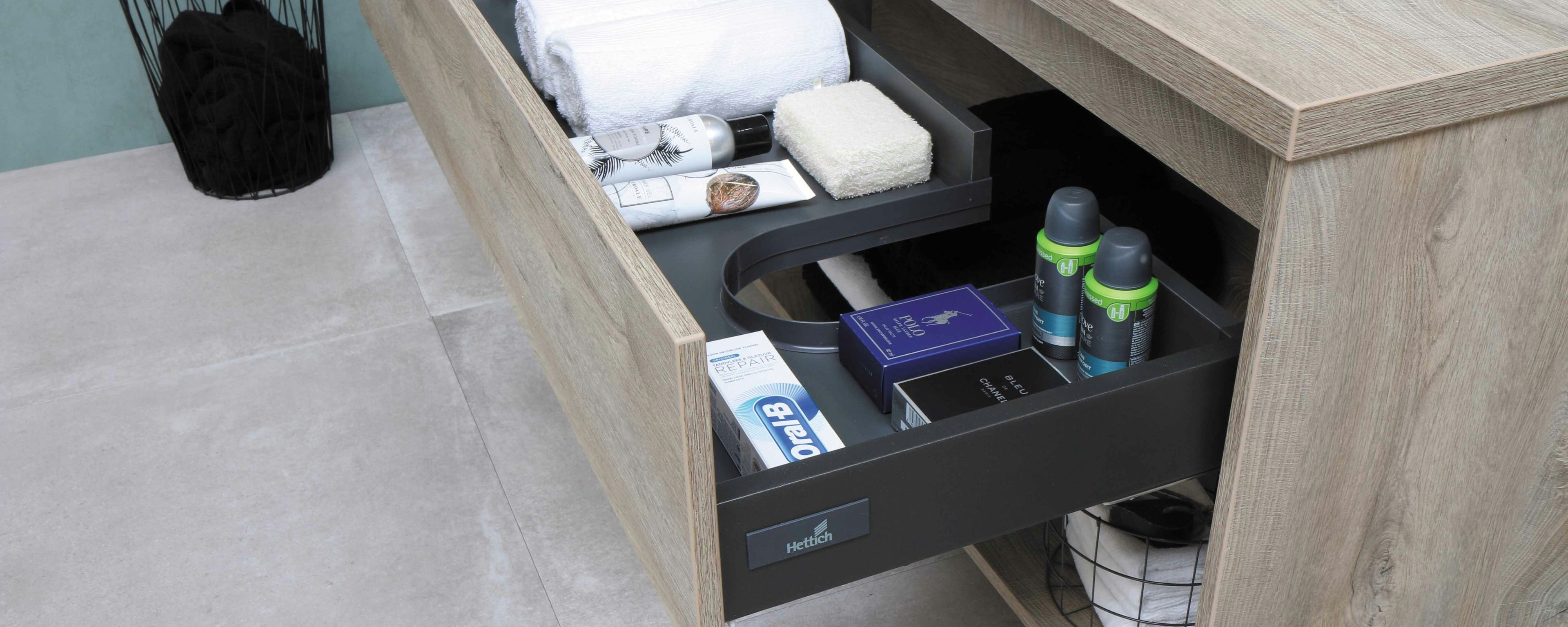 a bathroom vanity with a drawer open filled with towels and toiletries .