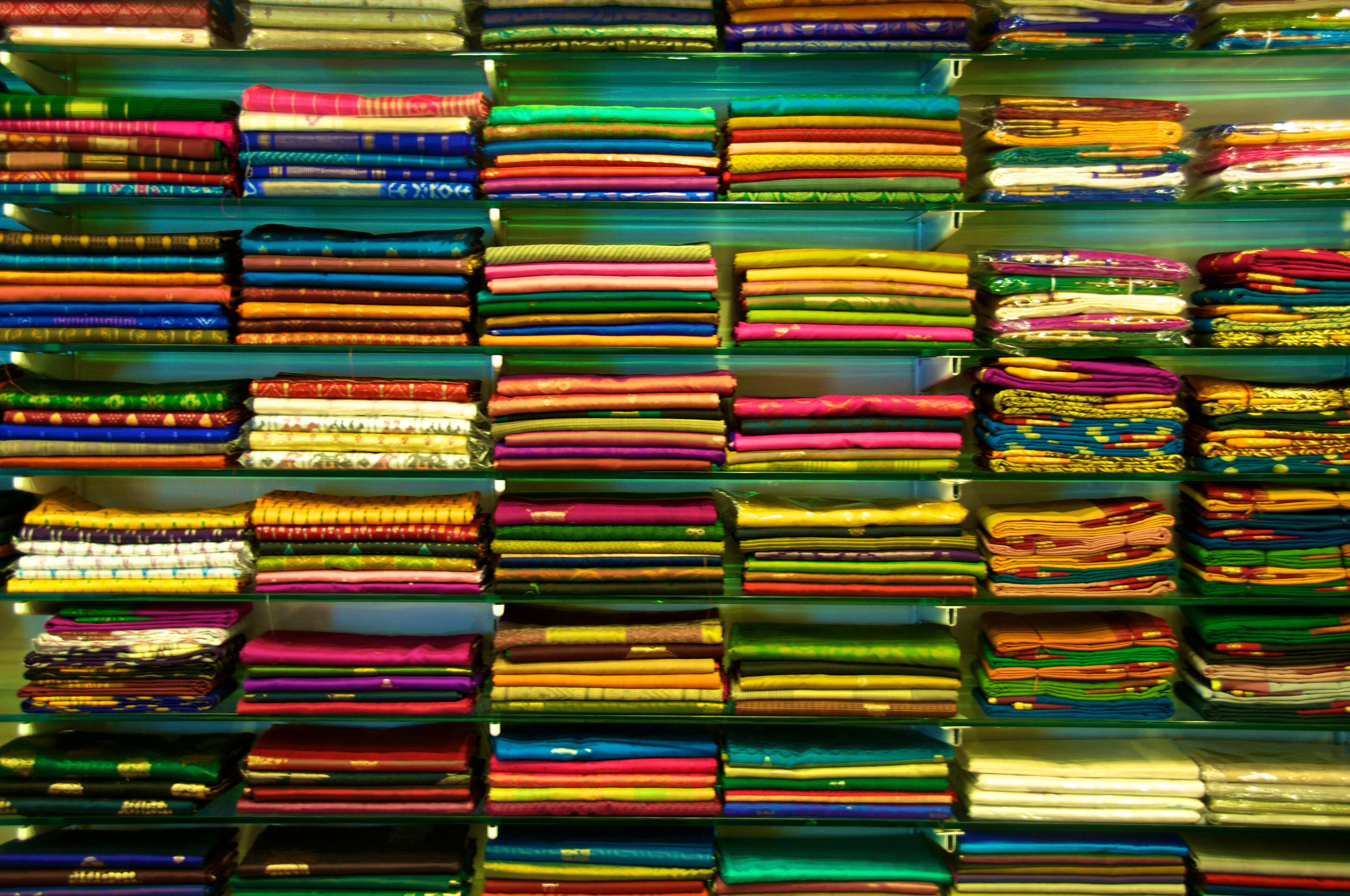 Shelves of folded sarees in many colours