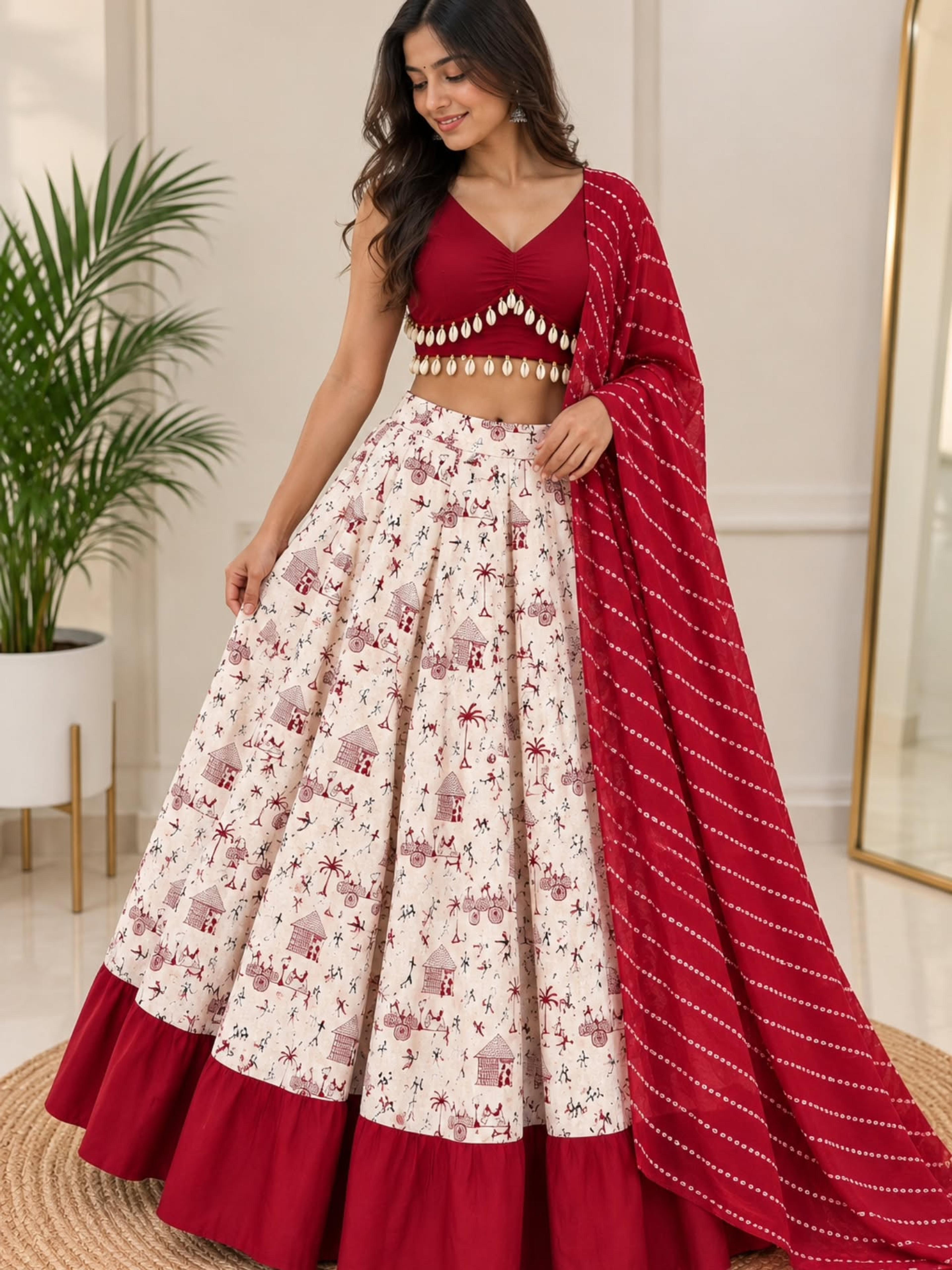 Model in an ivory folk-print lehenga with a red border, embellished red choli and Bandhani-style dupatta