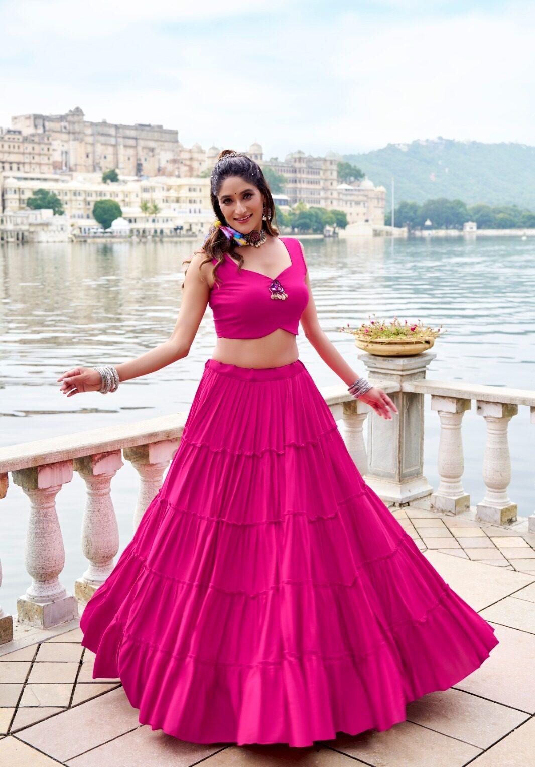 Model turning in a rani pink tiered rayon lehenga with a mirror-work blouse