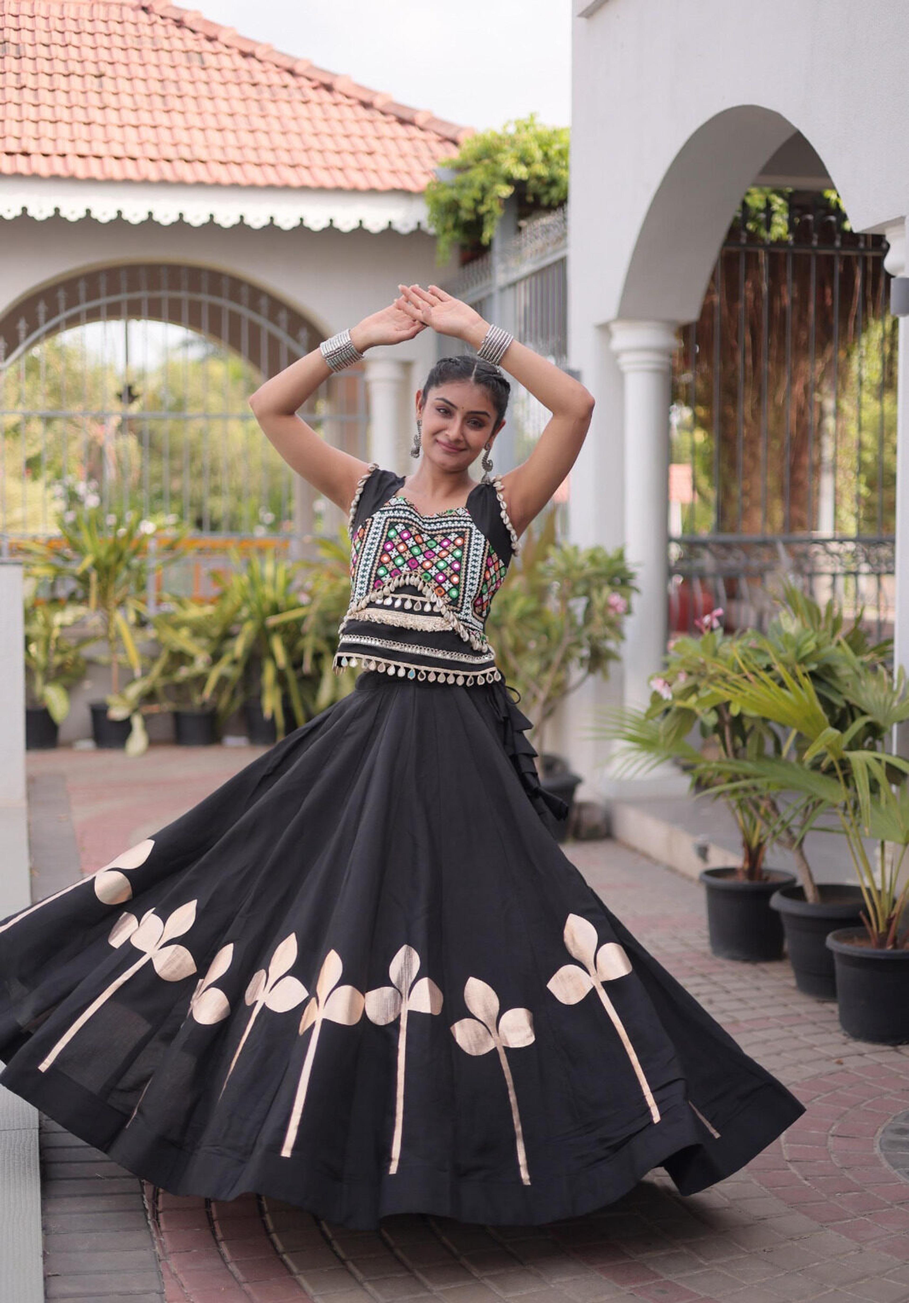 Model dancing in a black Roman silk chaniya choli with cream gota leaf work around the hem