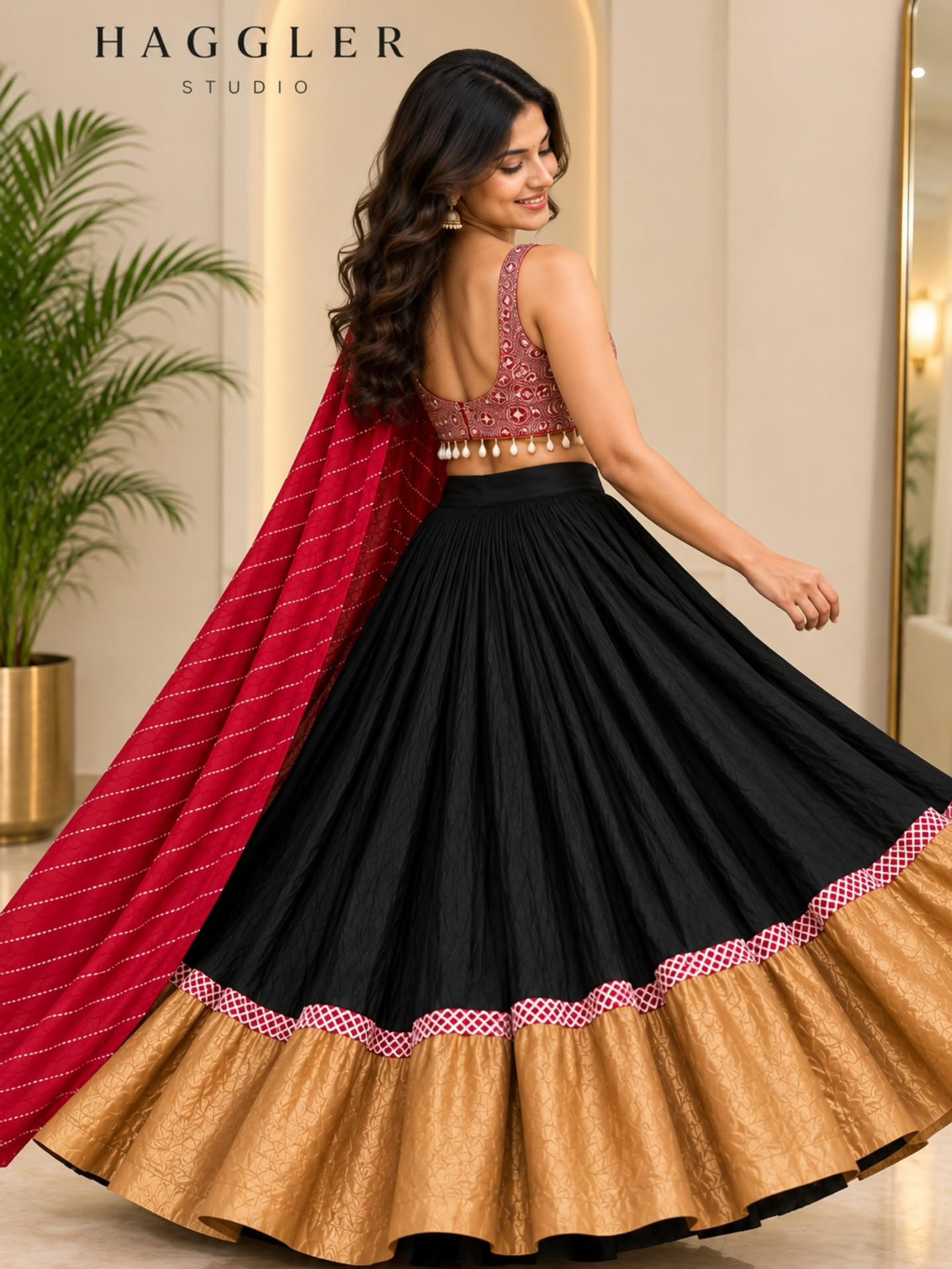 Model twirling in a black chaniya with a wide gold border, embroidered red choli and red striped dupatta