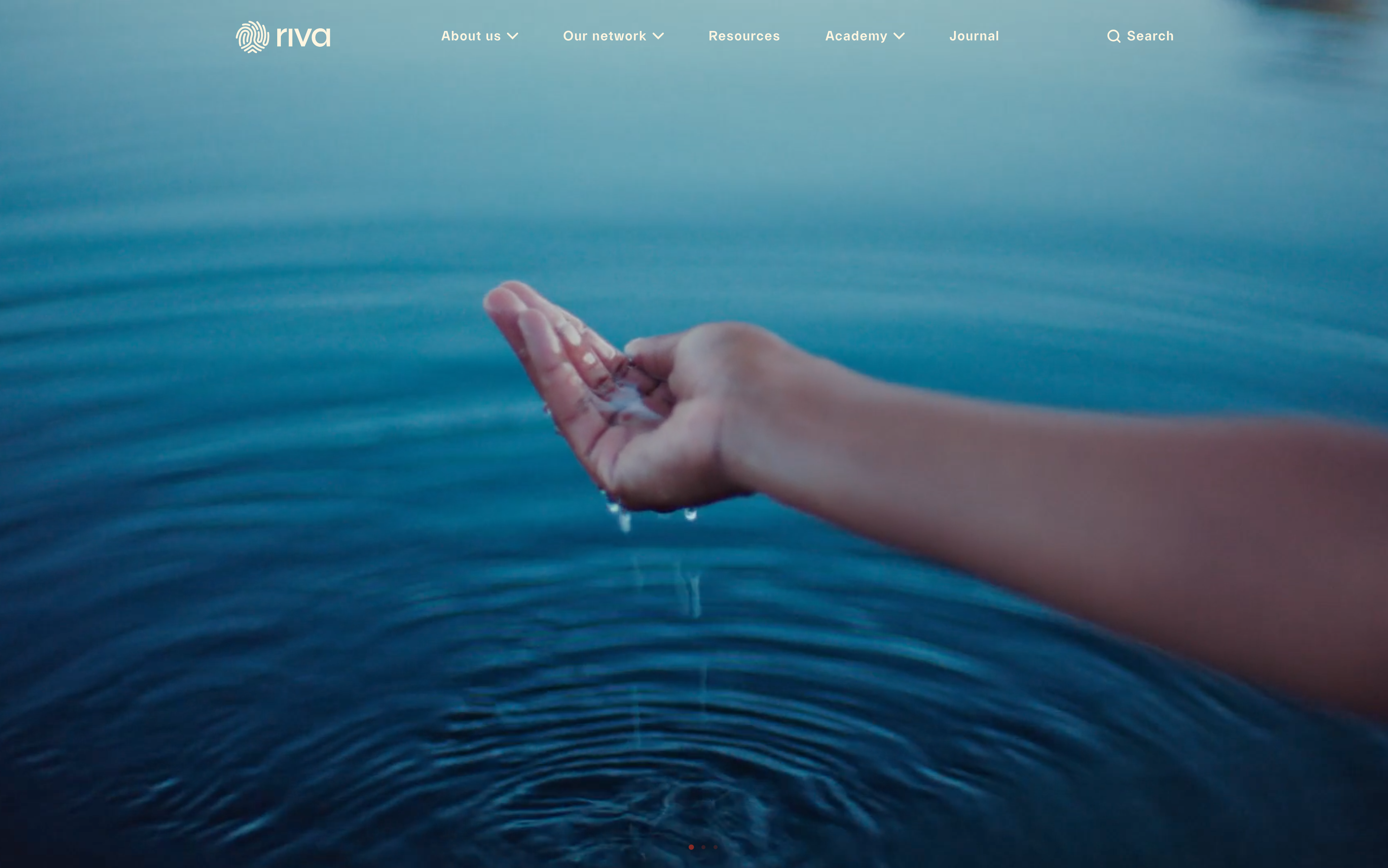 Hand holding water dripping into water causing ripples