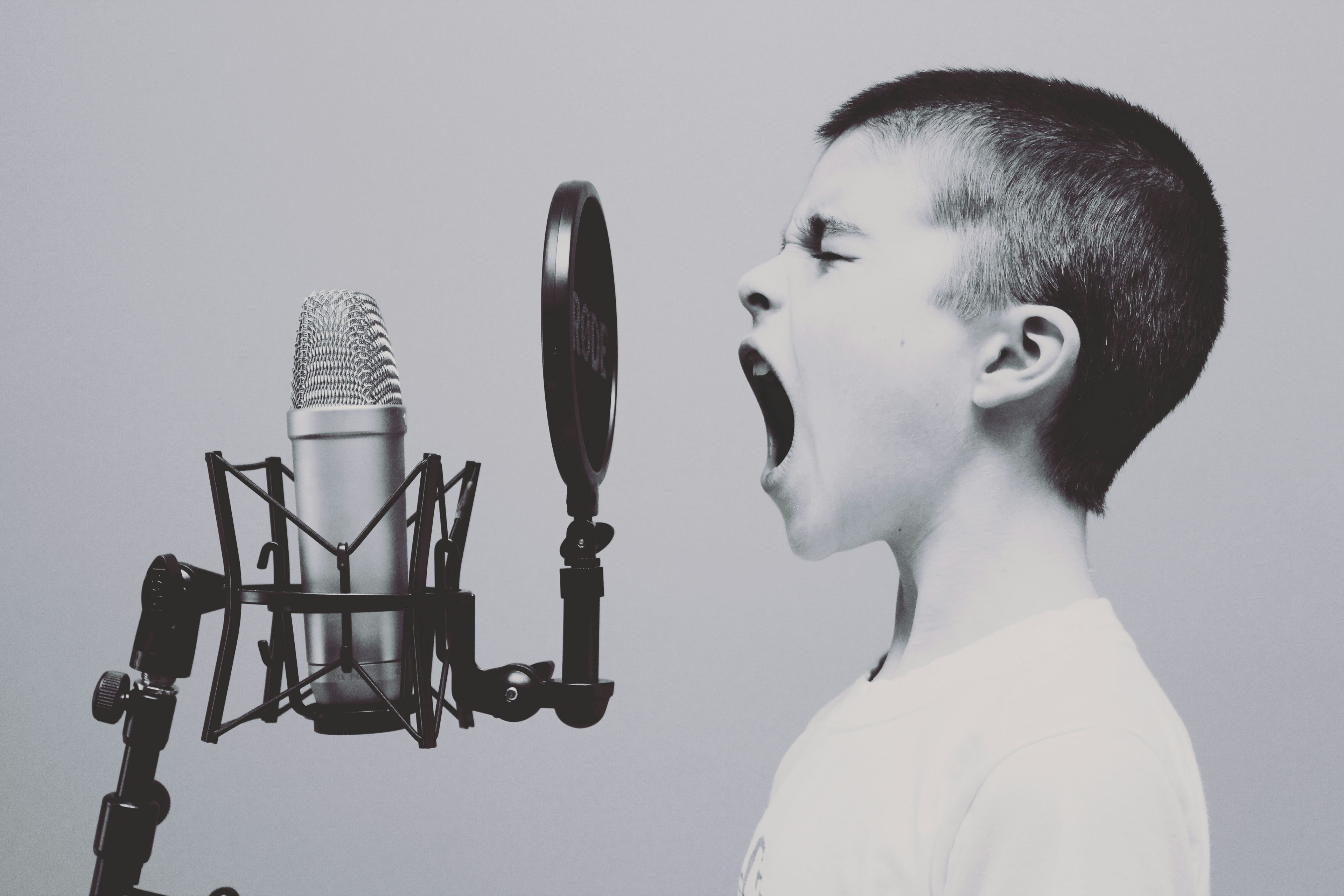 a young boy is singing into a microphone with his mouth open .
